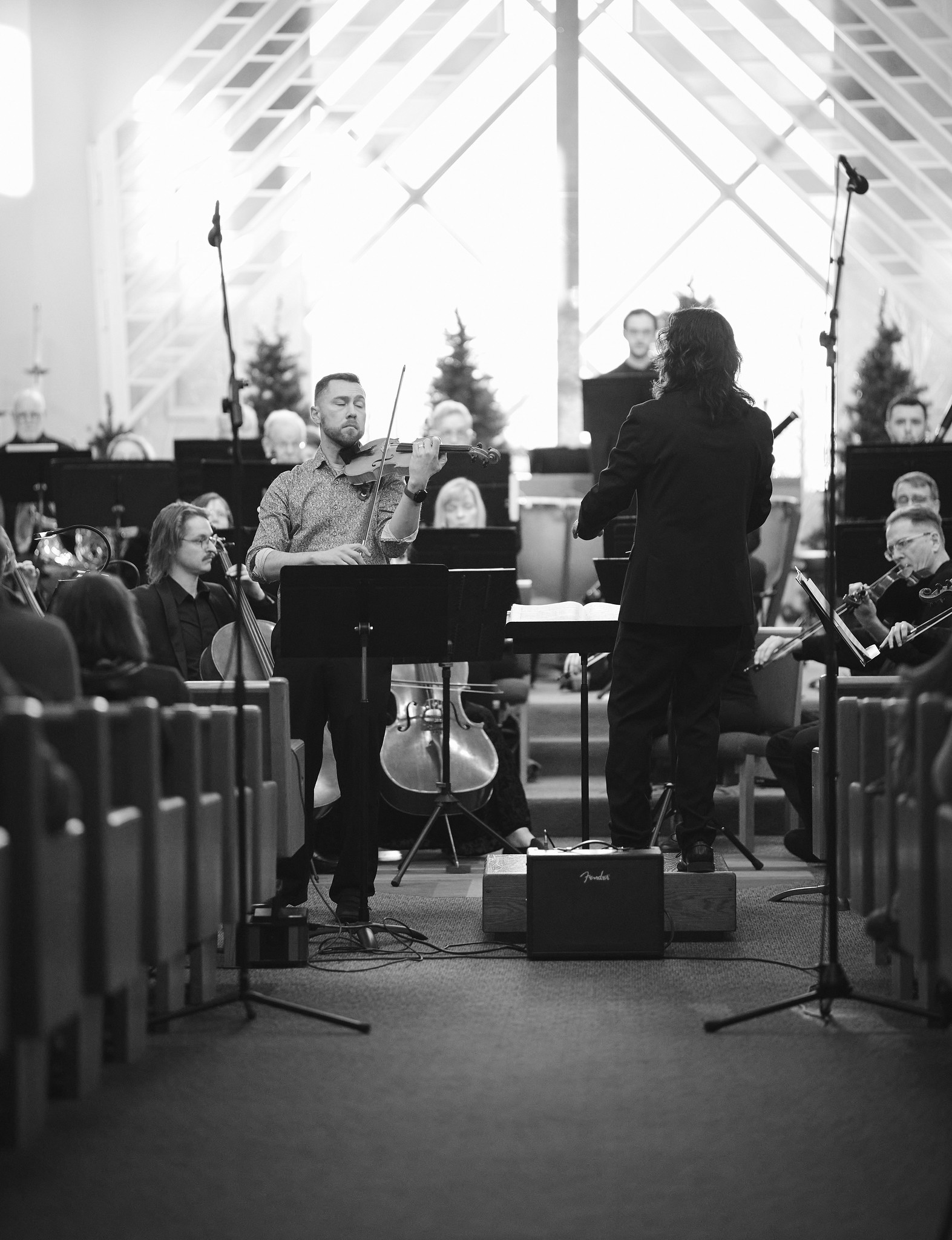 William Samorey performing violin with orchestra in front of stained glass